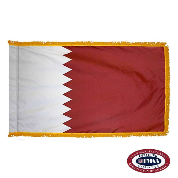 The indoor Qatar flag has 3 sides of gold fringe around small white and larger red fields. They are divided by a serrated line. FMAA Certified Made in America seal.