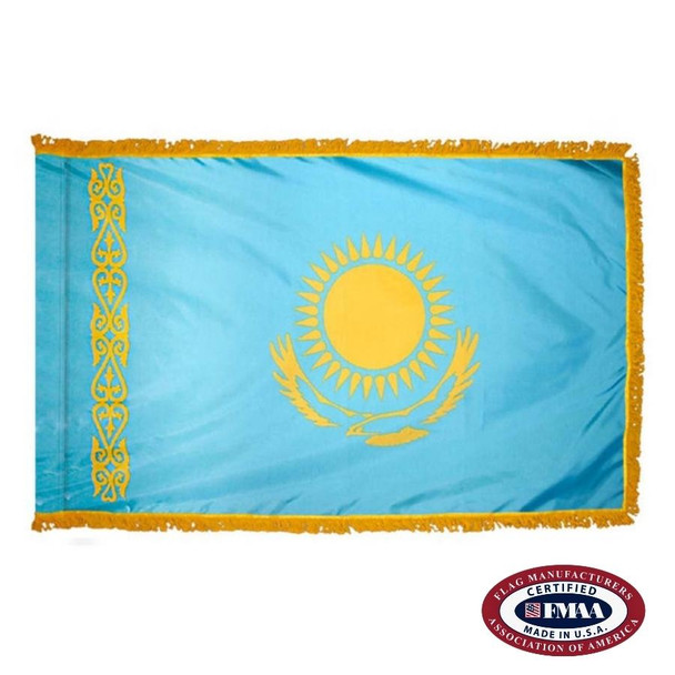 The indoor Kazakhstan flag has 3 sides of gold fringe around a light blue field with a yellow sun and eagle in the center. FMAA Certified Made in America seal.