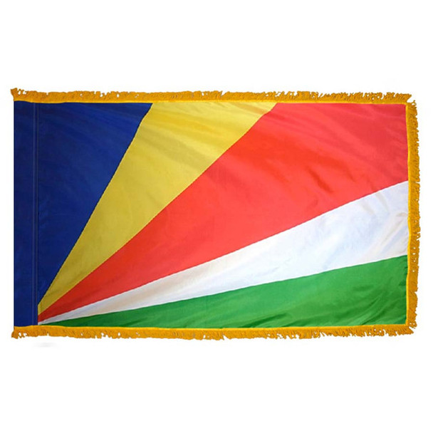 The indoor Seychelles flag has 3 sides of gold fringe around 5 blue, yellow, red, white, and green rays emanating from the bottom left.