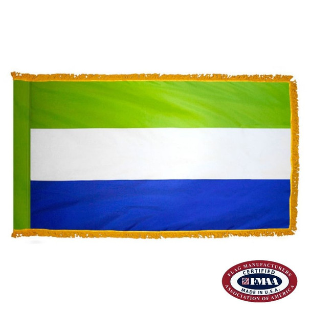 The indoor Sierra Leone flag has 3 sides of gold fringe around a horizontal green, white, and blue tricolor. FMAA Certified Made in America seal.