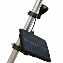 A black solar flagpole light is attached to a silver pole. The lightbulb is pointed upwards, and the solar panel is connected through a wire.
