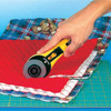 Close-up of a hand using the OLFA 60mm Straight Handle Rotary Cutter to cut through multiple layers of a quilt sandwich, showing the cutter's blade and yellow handle.