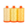 Three large spools of Aurifil Sicily 50wt Egyptian cotton thread in a gradient of yellow colors on a white background.