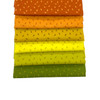 The image shows the 6 orange, yellow and green cascading fabric squares with tiny lightening bolt patterns. A great blender fat quarter pack fromt he Atomic collection.