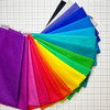 Fan of Phosphor Electric 10-inch fabric squares arrayed on a gridded cutting mat, showcasing a vibrant colour gradient.