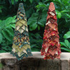 Pair of no-sew fabric trees in prints from Makower's Golden collection in green and red, displayed outdoors in a garden setting.
