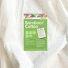 A close-up of Matilda's Own 50/50 Bamboo Quilt Wadding with its green product label placed on top. The label highlights key features, including "Bamboo / Cotton," "Machine Washable," and "Prewashed & Preshrunk." It also states that the wadding is "New & Improved" and measures 30m x 2.4m. The packaging includes a description of why bamboo cotton wadding is beneficial, mentioning its natural softness, breathability, and eco-friendly properties. The care instructions and key product features are visible at the bottom of the label, alongside the Victorian Textiles logo and website information. The wadding itself appears soft, off-white, and textured.