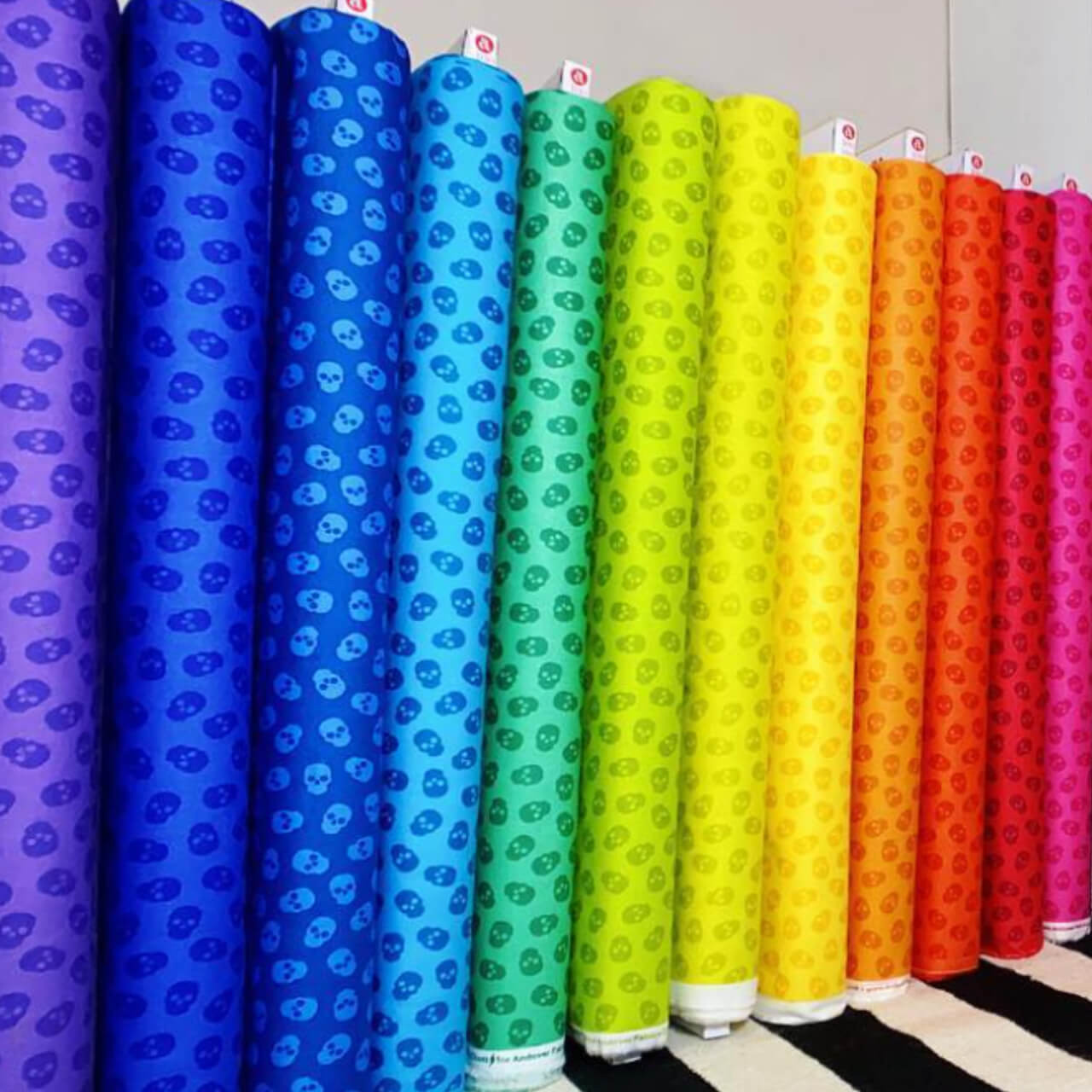 A line up of the tainted Love fabric rolls in a rainbow colour order