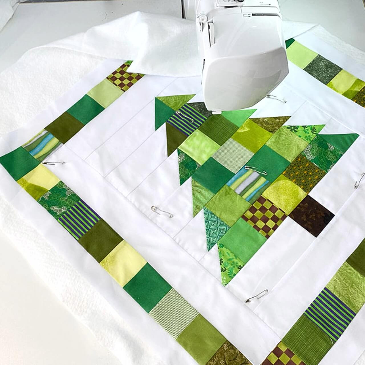 Scandi Festive Tree quilt being quilted on a sewing machine with safety pins holding layers in place.