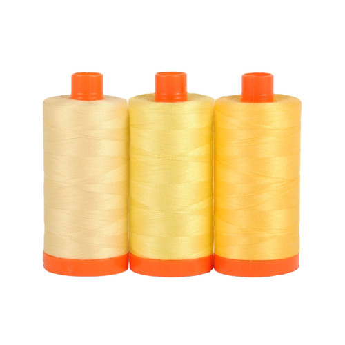 Three large spools of Aurifil Sicily 50wt Egyptian cotton thread in a gradient of yellow colors on a white background.