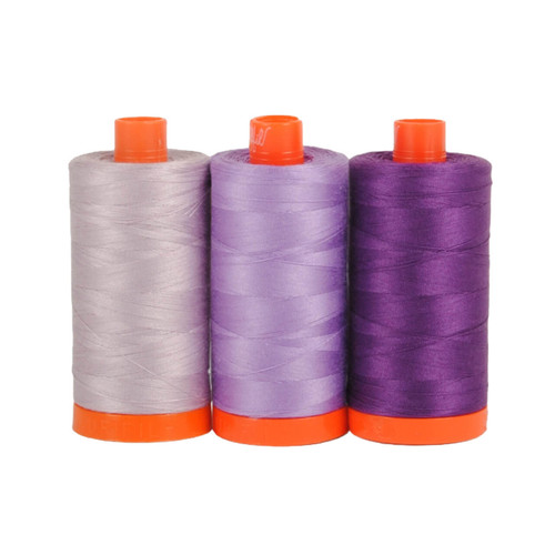 Three large spools of Aurifil Amalfi 50wt Egyptian cotton thread in coordinating shades of purple on a white background.