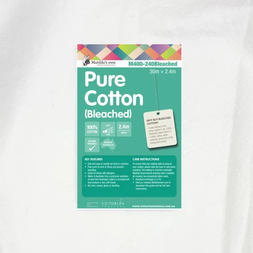 Matilda’s Own 100% Cotton Wadding product sheet displayed on the fabric, showing key benefits, care instructions, and label indicating a 30m x 2.4m roll.