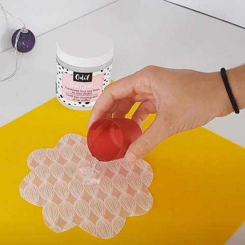 Hand applying OdiCoat gel to fabric with Odif OdiCoat jar in background.