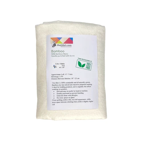 A packaged Matilda's Own Bamboo COtton Quilt Wadding in baby size (48" x 60"), wrapped in eco-friendly plastic-free packaging. The front label displays key product details, including its composition of 100% bamboo fibres, needle-punched with scrim. The packaging highlights features such as an approximate loft of ⅛ inch (3mm), a shrinkage rate of 2.5%, and a maximum stitch distance of 10 inches (25cm). The label also describes the wadding’s sustainability, antibacterial properties, and softness, making it suitable for bedding and baby quilts. A green "100% Plastic Free" logo is visible, reinforcing the environmentally friendly packaging.