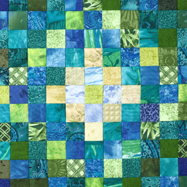 A colourful patchwork quilt featuring an array of blue and green 5 inch Charm Squares in various patterns.