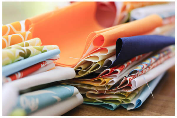 A colourful assortment of pre-cut fabric scraps in various sizes and patterns, ideal for quilting and sewing projects.