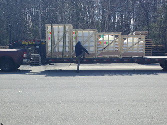 Wood-crated Velux CMD2 skylight loaded on a flatbed trailer with a worker nearby
