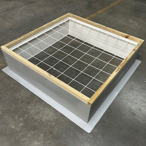 Assembled roof curb with a wire safety grate on top, photographed indoors on a warehouse floor