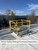 Closed ladder hatch with yellow safety railing installed on a white membrane roof