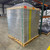 Palletized stack of flat-packed skylight curb components with a wrapped dome unit on top in a warehouse