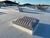Sunoptics SVT2 smoke vent on a white membrane roof with additional vents and palm trees visible behind it
