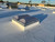 Sunoptics SVT2 smoke vent on a white roof with a rooftop HVAC unit and trees visible in the background