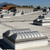 Wide view of several domed roof vents across a white TPO roof with snow-capped mountains in the distance
