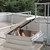 Person climbing through an open roof hatch with a safety railing on a gravel rooftop