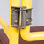 Close-up of the spring-loaded self-closing hinge mechanism on the yellow guardrail gate