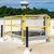 Roof hatch with yellow Bil-Guard rail system installed on a white membrane roof, water tower in background
