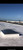 Domed skylight with a protective wire guard installed on a white commercial roof under blue sky