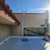 KattSafe RL30 ladder mounted against a tan stucco wall leading up to a flat roof, with a safety cone nearby