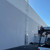 KattSafe RL30 ladder mounted on a white metal building wall, with a utility truck parked alongside