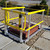 Yellow self-closing gate guardrail around a roof hatch with residential rooftops in the background