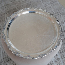 Intricate engraving across the platter's surface reveals Sheridan's commitment to craftsmanship, as elaborate scrolls, lattice patterns, and floral elements dance across the silver in a symphony of decorative detail.