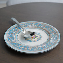 This vintage bread and butter plate features an outer rim with  decorative bands, including a thin black and white borders and bright turquoise.  This bread and butter plate was made by Wedgwood in England and the pattern name is Florentine.