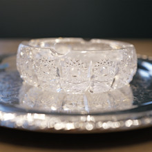 The ashtray's crystalline appearance comes alive with light, as each diamond-like facet catches and reflects illumination from every angle, creating a dazzling display reminiscent of fine Bohemian crystal.