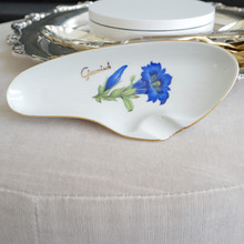 Vintage white porcelain ashtray with blue flower, gold rim, and gold Garmisch in interesting organic oval shape that nods to a MCM mid-century modern style.