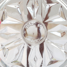Very close up view of a vintage glass and silver rimmed coaster showing  the Made in Italy impression on the glass