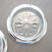 Close up view of a silver plated rimmed glass coaster that is Made in Italy