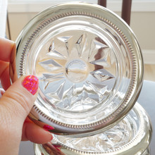 Close up view of a vintage Italian glass and silver plate coaster with sun shining through the back showing the Made in Italy stamp