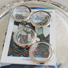 Set of three vintage Italian glass and silverplate coasters on top of an art book