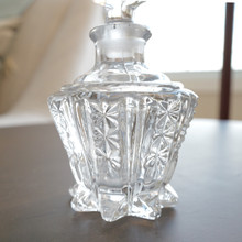 Footed vintage glass perfume bottle with textural geometric design in Art Deco style.