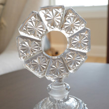 Perfume bottle topper with textural geometric design in round doughnut shape.