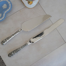 Back side of vintage cake serving set with cake knife and cake server by Godinger .  Both serving utensils are made with stainless steel blades and ornate silver plated handles.  These elegant pieces have a high gloss shine.