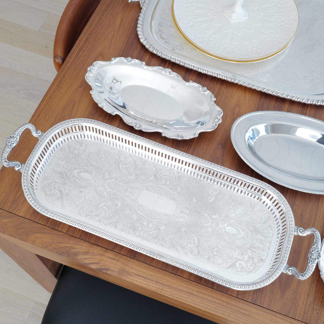 An oblong serving tray, also called a gallery tray.  This tray is a show piece of American craftsmanship featuring an ornate floral design, feet, handles, and perforated edges.