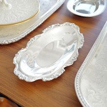 This vintage Wallace Royal Rose bread tray (model 9807) features an ornate floral and scrollwork border. Crafted in silver plate, its oval shape and scalloped edge make it a timeless piece for serving or display.
