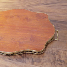 Serve in style with this vintage tray featuring a scalloped silhouette, brass handles, and intricate floral inlay.
