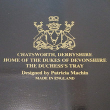 Made in England, this collectible tray features ornate gold scrollwork and a central floral bouquet on a striking black background.