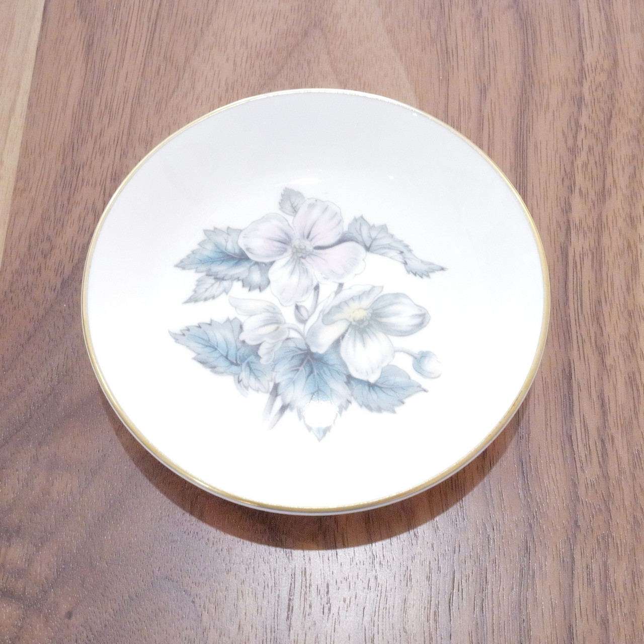 Features delicate blossoms in soft pastel hues with blue-green leaves.  Trimmed in elegant gold around the edge.